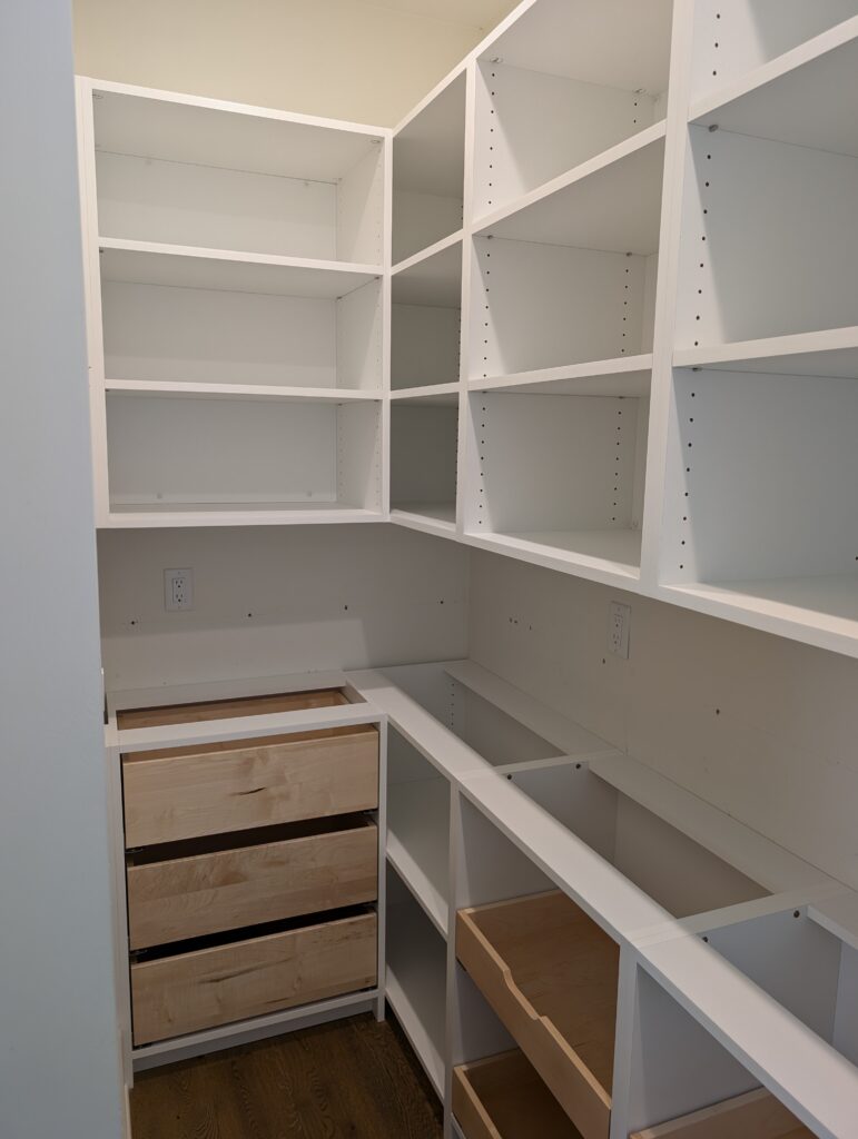 White walk-in pantry with full-height adjustable open shelving on both walls. The layout maximizes storage with a grid-like design, providing space for dry goods, kitchenware, or bulk items.